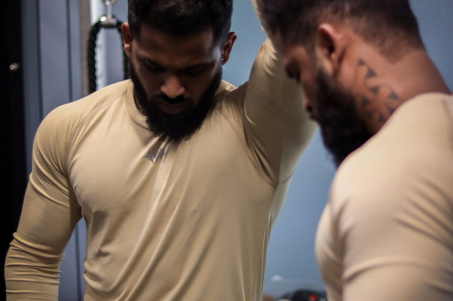 Two men in beige shirts interacting with each other in a room.